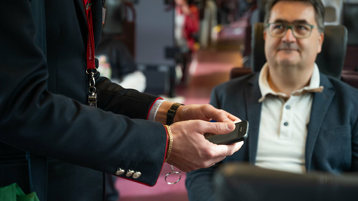 A ticket inspector checks a ticket using his smartphone.