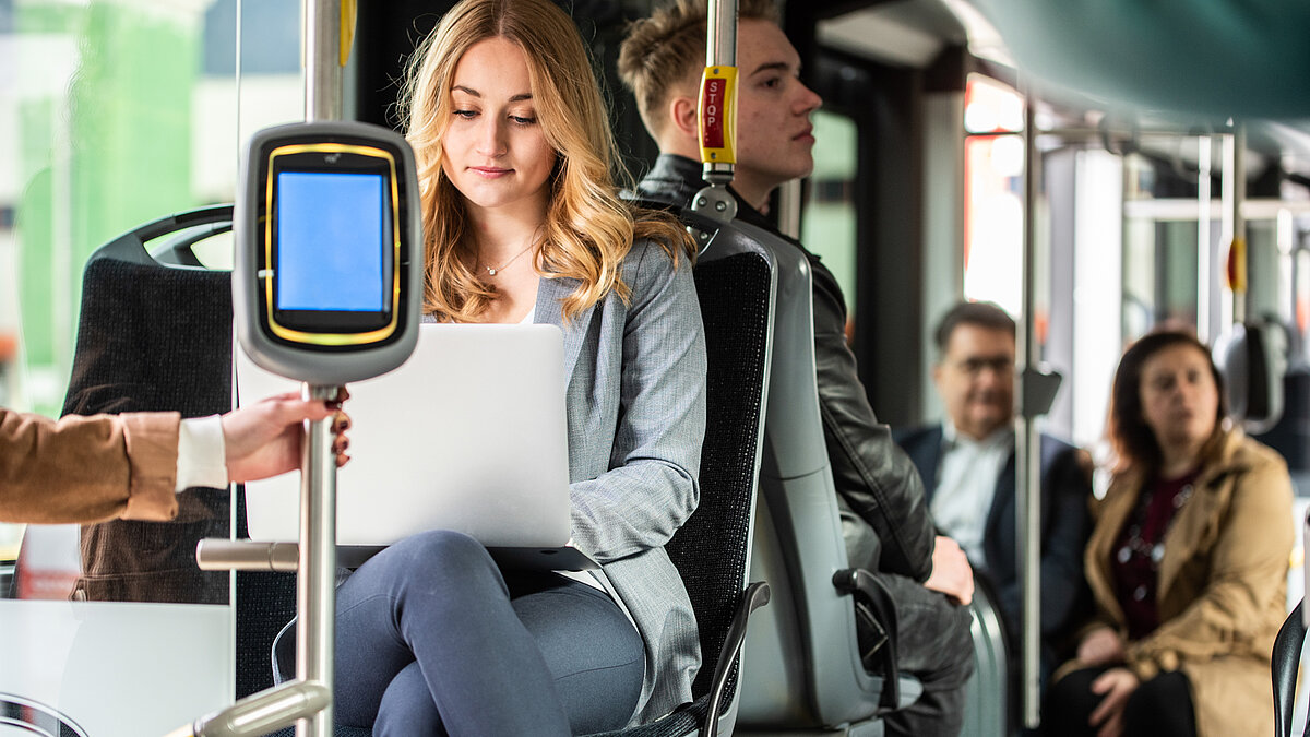 A woman is working on her laptop on the bus