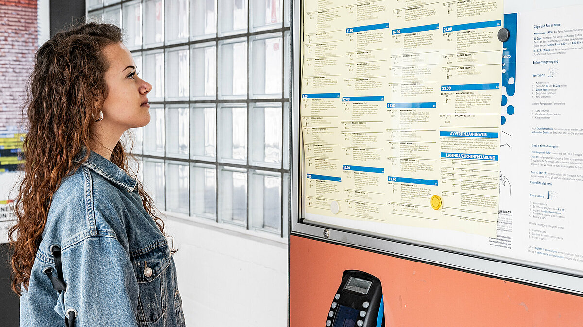 A girl is checking the train timetable at the station