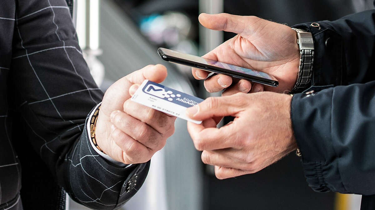 Detail of the hands of a ticket inspector and a passenger, while checking the ticket.